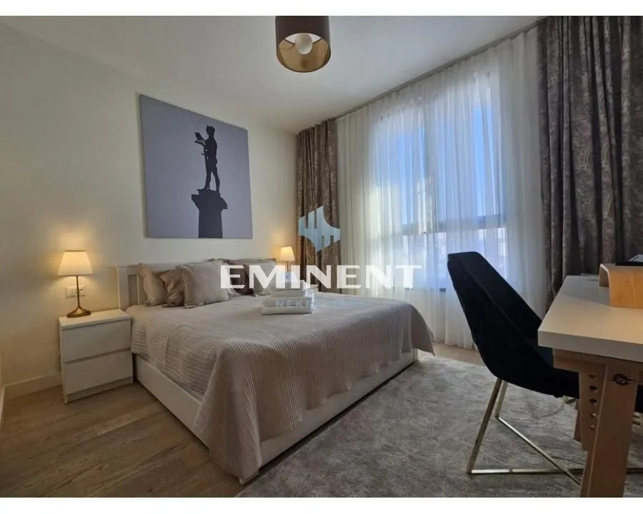 Furnished bedroom with a double bed, desk, and large window.