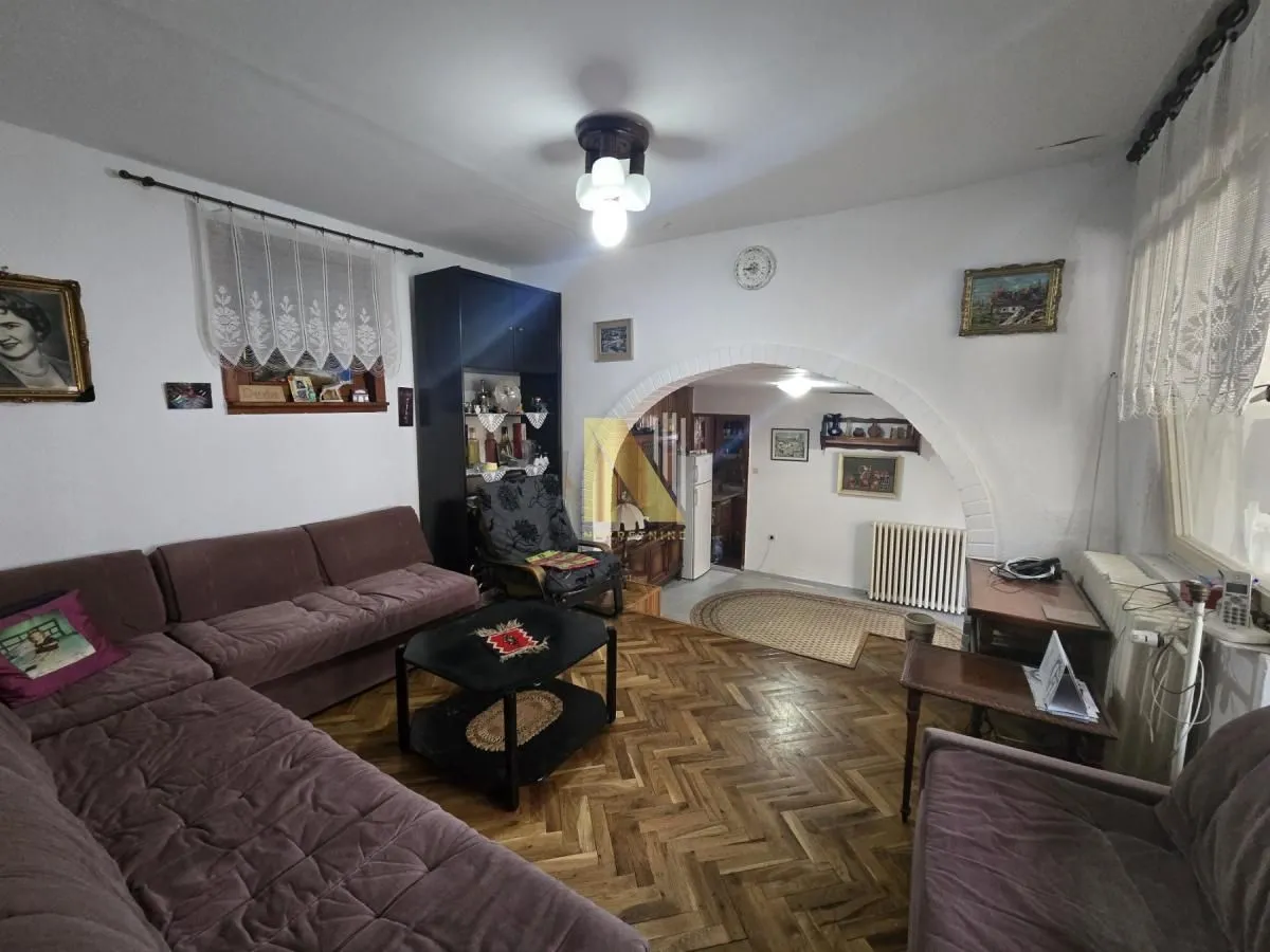 Dnevna soba sa garniturom i drvenim podom.