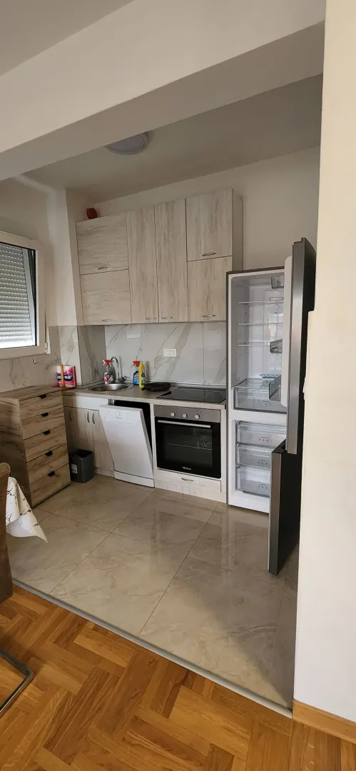 Manja kuhinja sa svijetlim drvenim elementima i ugrađenim kućnim aparatima.