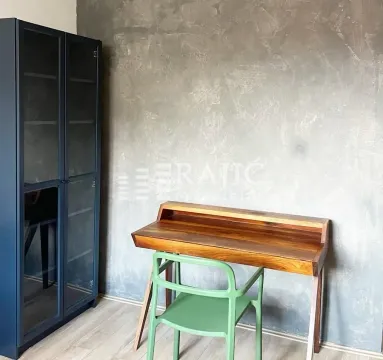 Study room with a wooden desk, green chair, and dark wardrobe. - image 3