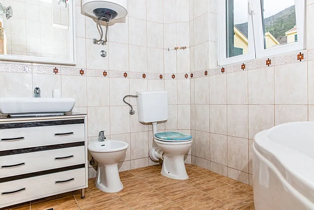 Svijetlo kupatilo sa bideom, toaletom i ormarićem sa umivaonikom.