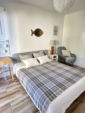 Decorated bedroom with a double bed, armchair, and desk. - image 4