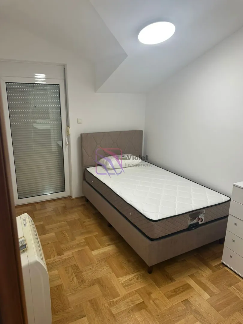 Small bedroom with a bed and parquet flooring.