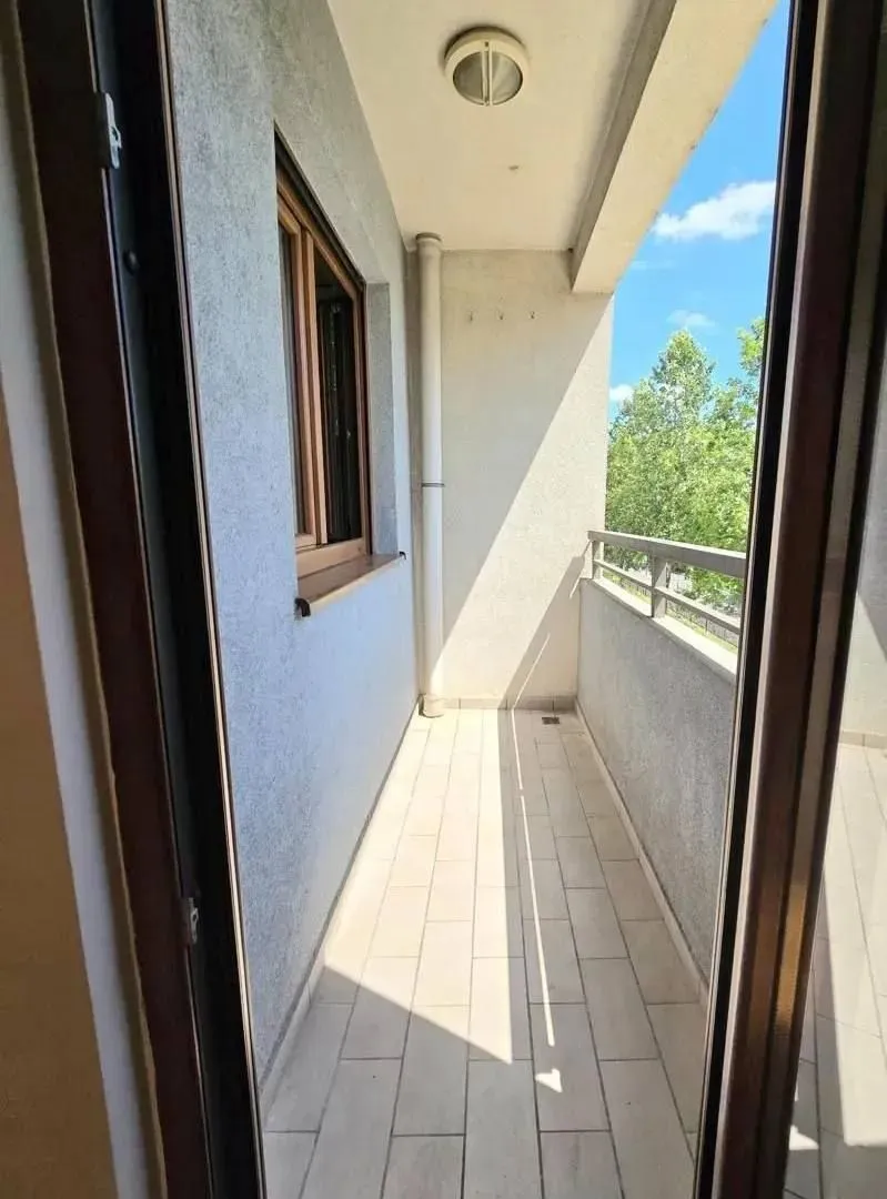 Pogled na prostrani natkriveni balkon sa pločicama i metalnom ogradom.