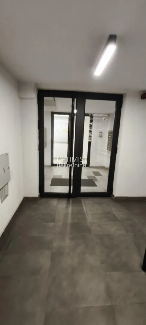Ulaz u stambenu zgradu sa staklenim vratima.