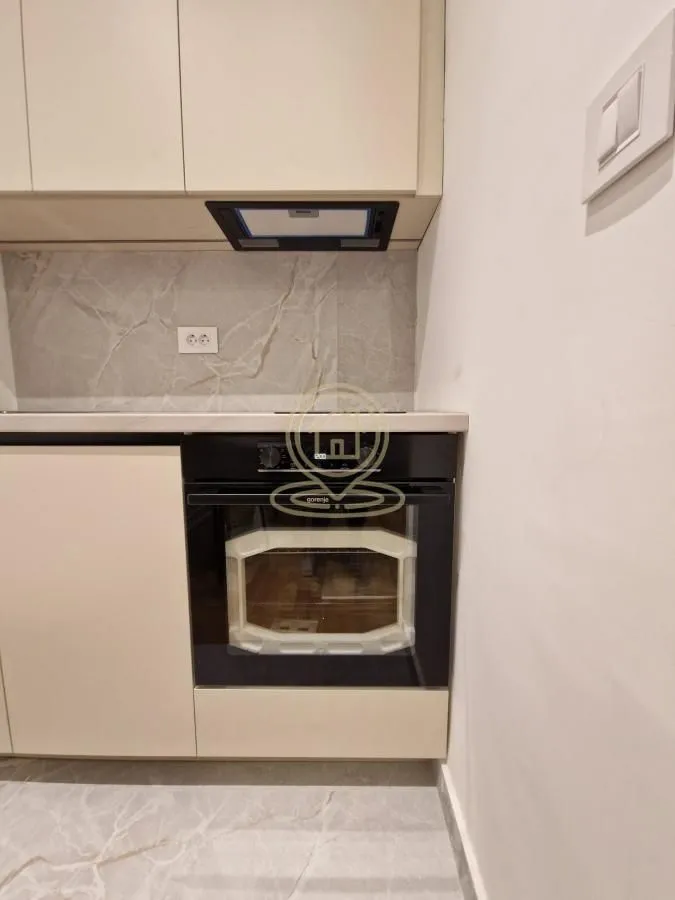 Dio kuhinje sa ugradnom rernom i elementima u bež boji.