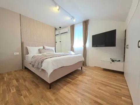 Moderna spavaća soba sa bračnim krevetom, drvenim podom i zidnim televizorom. - image 6