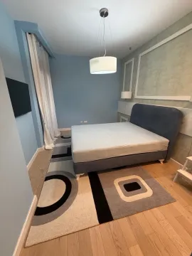 Modern bedroom with a double bed, blue walls, and a patterned rug. - image 5