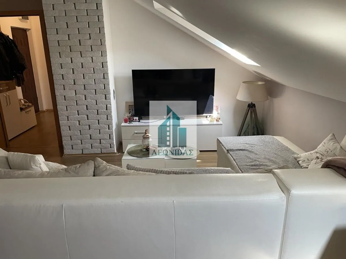 Attic living room with sofa and TV.