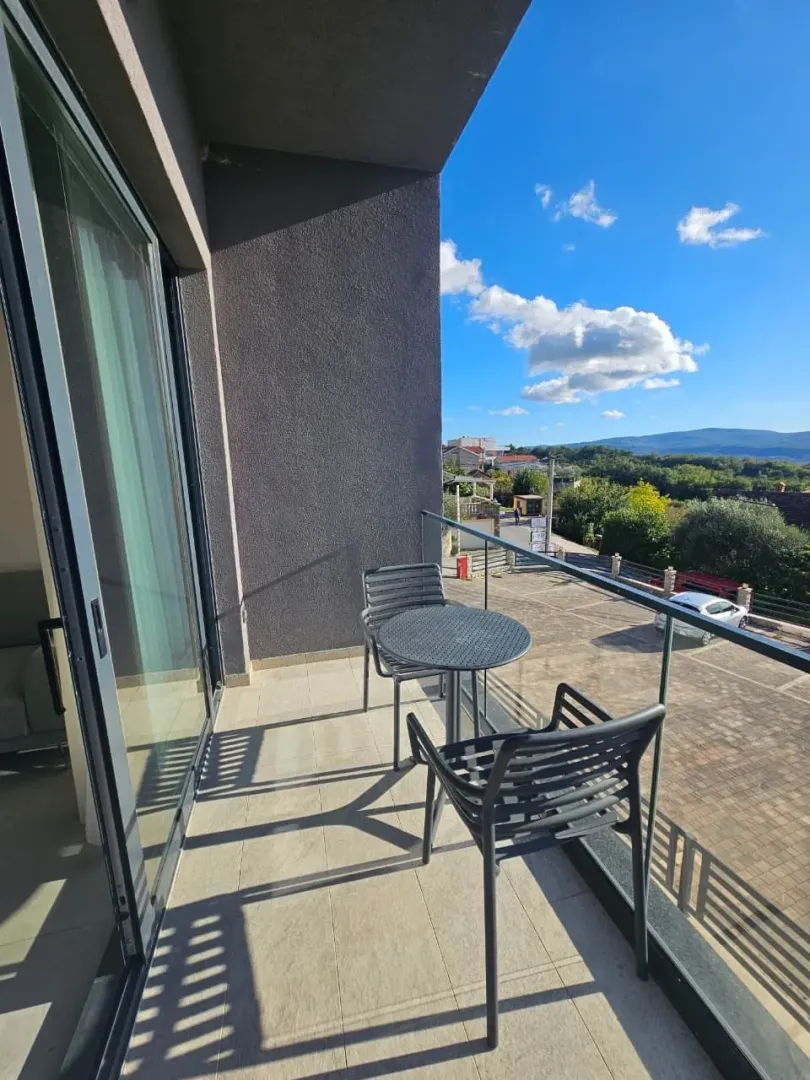 Manji namješteni balkon sa stolom i dvije stolice i pogledom na okolinu.