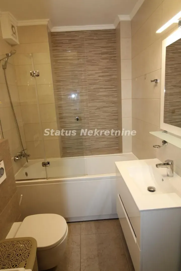 Modernly equipped bathroom with bathtub, shower screen, washbasin and toilet.