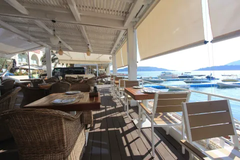 Covered restaurant terrace with a view of the sea and boat slips. - image 8
