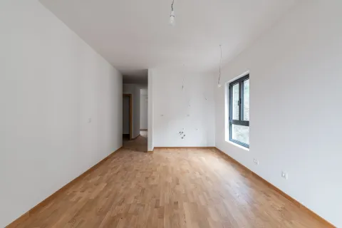 Prazna soba sa bijelim zidovima, drvenim parketom i prozorom. - image 5