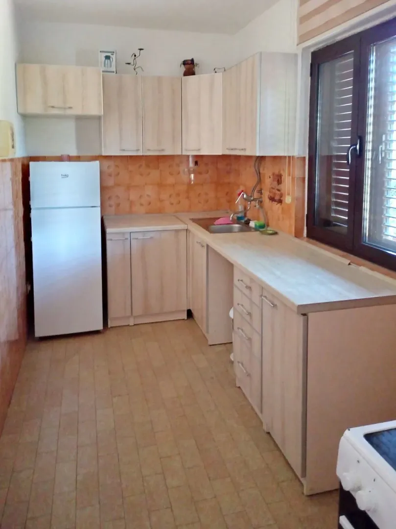 Small kitchen with light wood cabinets and a white refrigerator.
