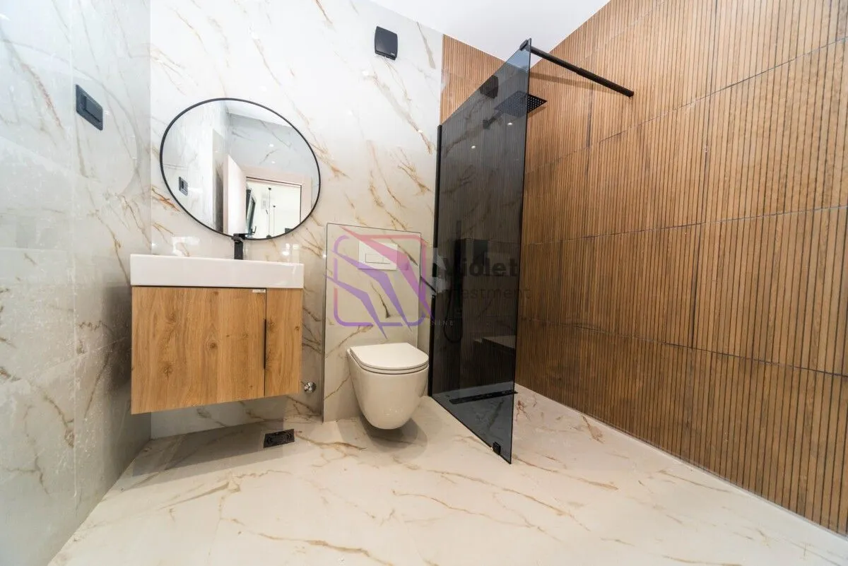 Moderno opremljeno kupatilo sa tuš kabinom, umivaonikom i WC šoljom.