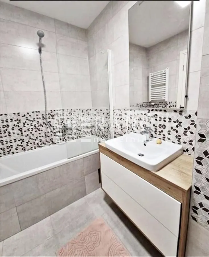 Modern bathroom equipped with a bathtub, washbasin, and mirror.