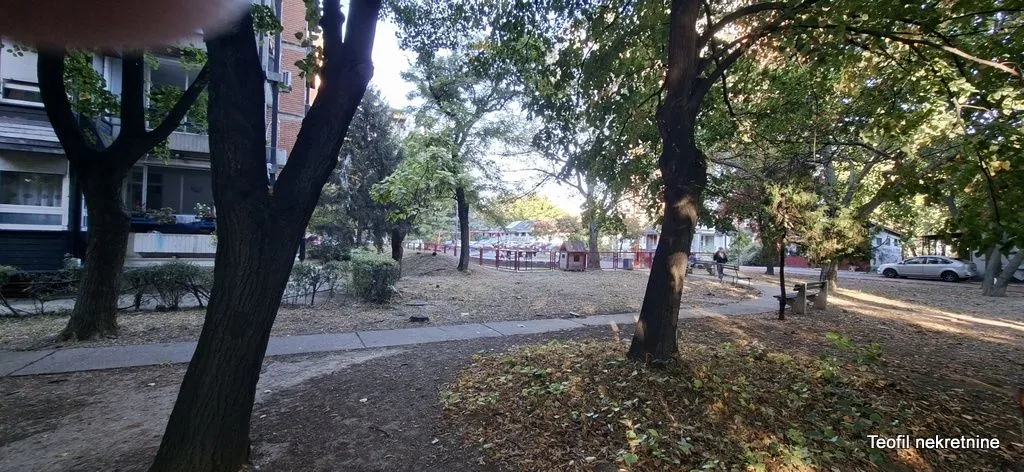 Zelena površina i drveće u dvorištu ispred stambene zgrade.