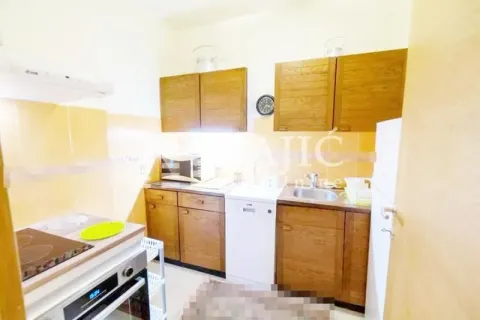 Small kitchen with wooden cabinets and built-in appliances. - image 2