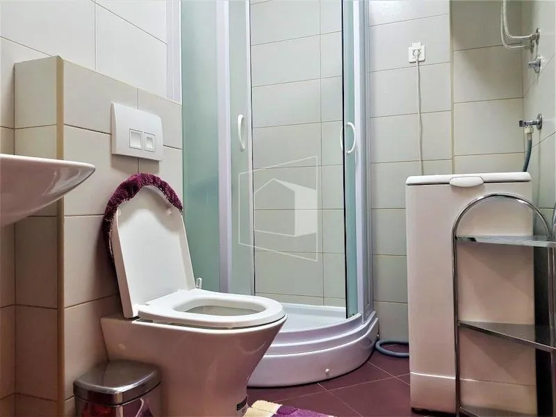 Manje kupatilo sa tuš kabinom, WC šoljom i veš mašinom.