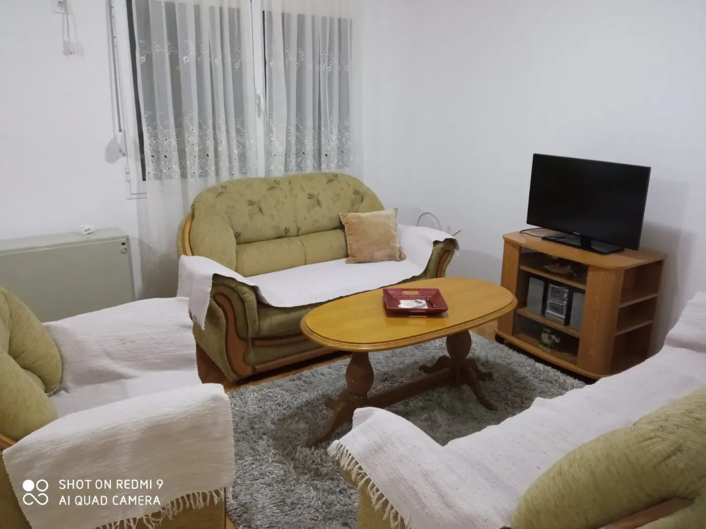 Living room featuring a green sofa set, wooden coffee table, and television.