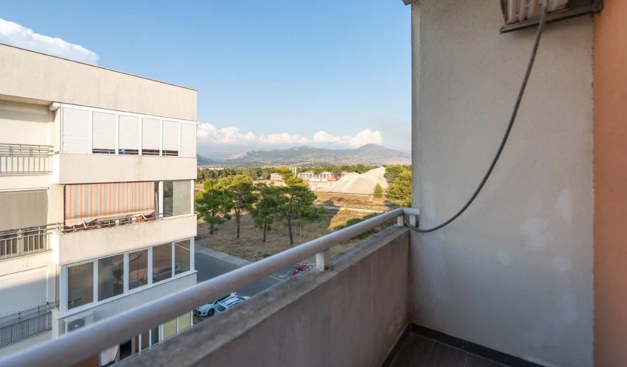 View from the balcony overlooking the neighboring building and surrounding landscape.