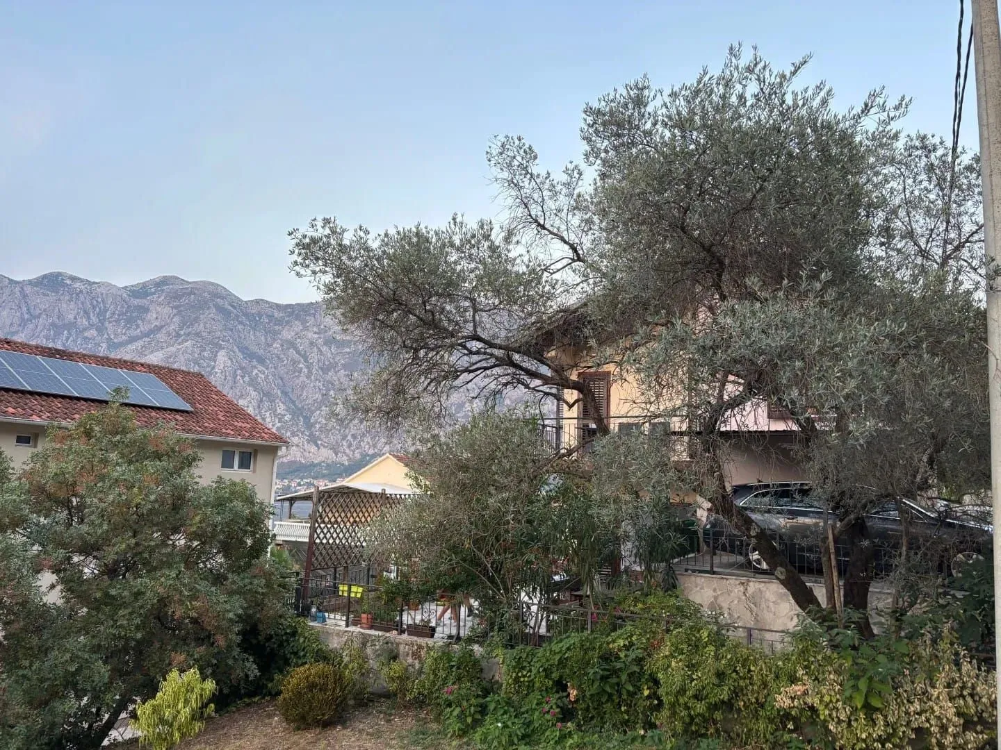 Pogled na dvorište i okolne kuće sa brdima u pozadini.