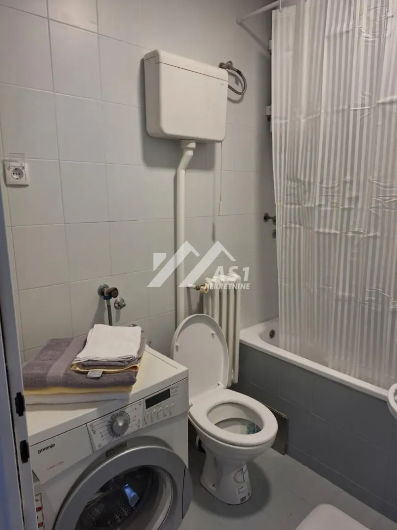 Small bathroom with bathtub, toilet, and washing machine.