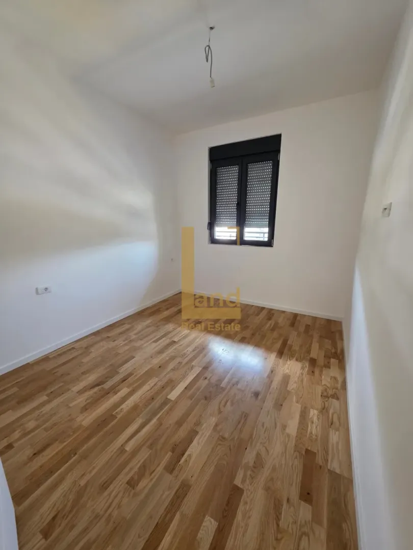 Prazna soba sa parketom i prozorom.
