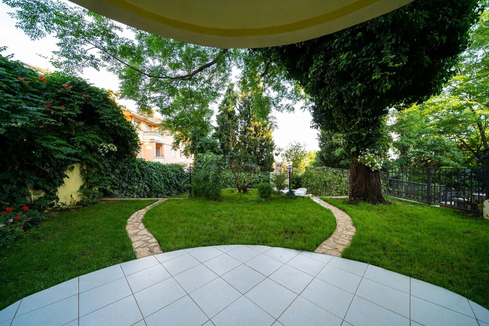 Landscaped yard with lawn and path viewed from a terrace.