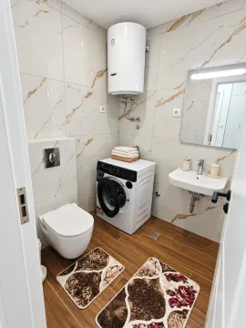 Savremeno opremljeno kupatilo sa tuš kabinom, umivaonikom i veš mašinom. - image 7