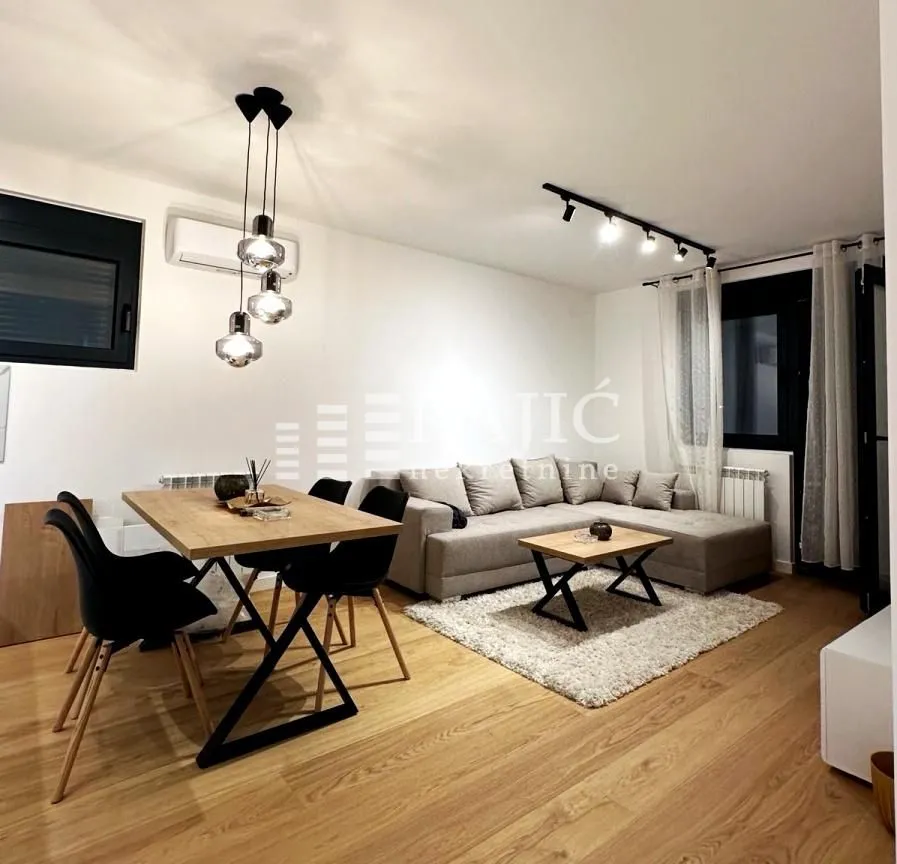 Modern living room with a sofa, dining table, and hardwood flooring.