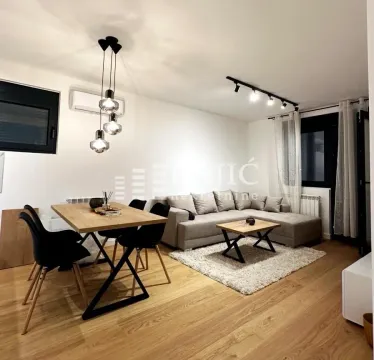 Modern living room with a sofa, dining table, and hardwood flooring. - image 3