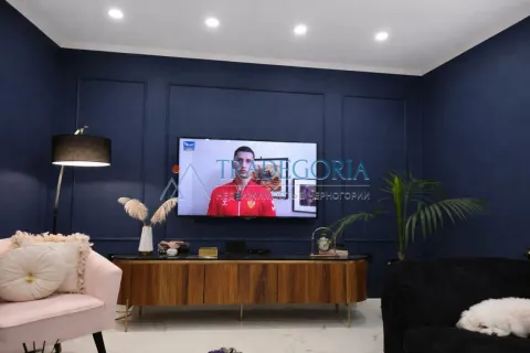 Dnevna soba sa tamnoplavim zidovima, televizorom i stilskim namještajem. - image 10