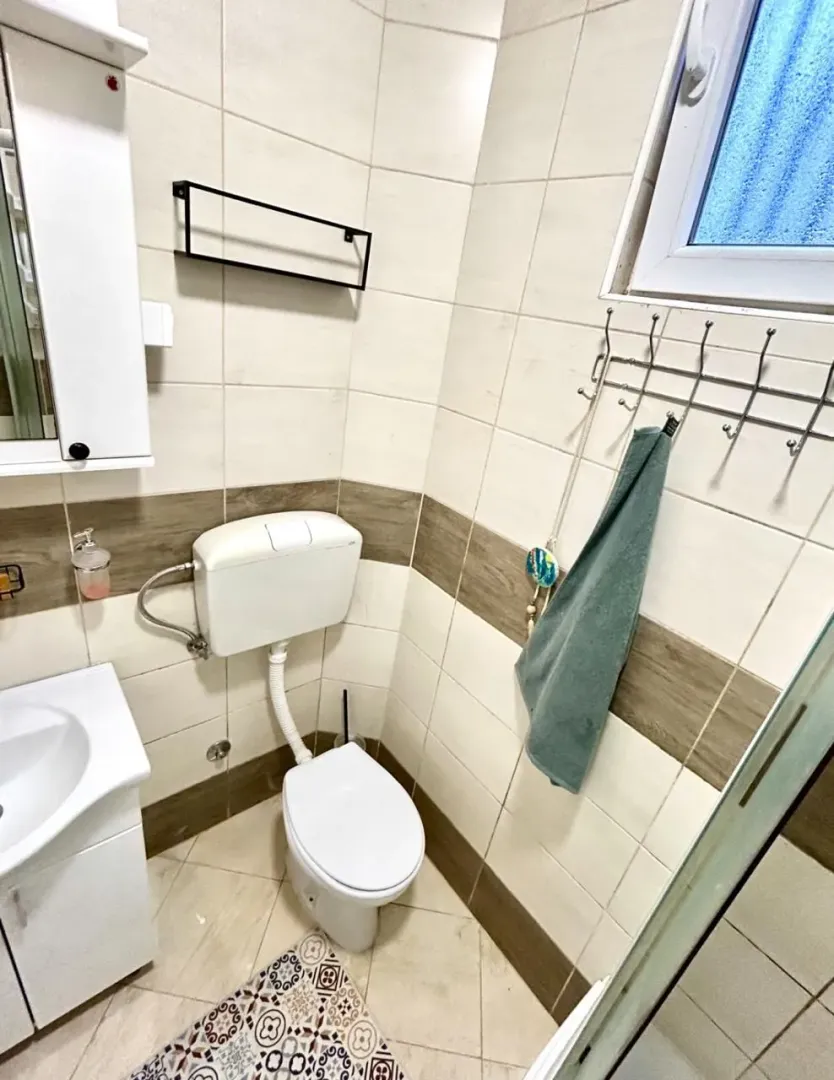 Manje kupatilo sa WC šoljom, umivaonikom i pločicama.