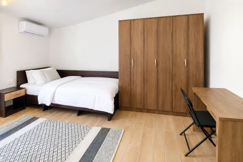 Furnished bedroom with a bed, a large wooden wardrobe, and a desk. - image 18