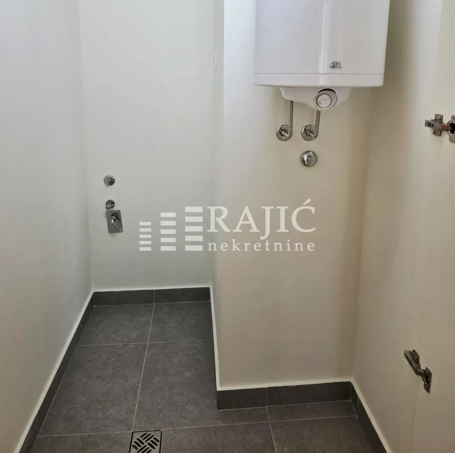 Smaller bathroom with tiling and a water heater.