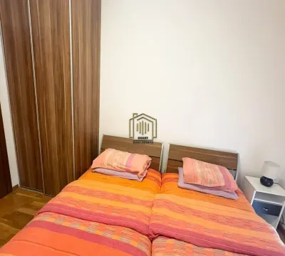 Spavaća soba sa bračnim krevetom, drvenim ormarom i noćnim stočićem. - image 2