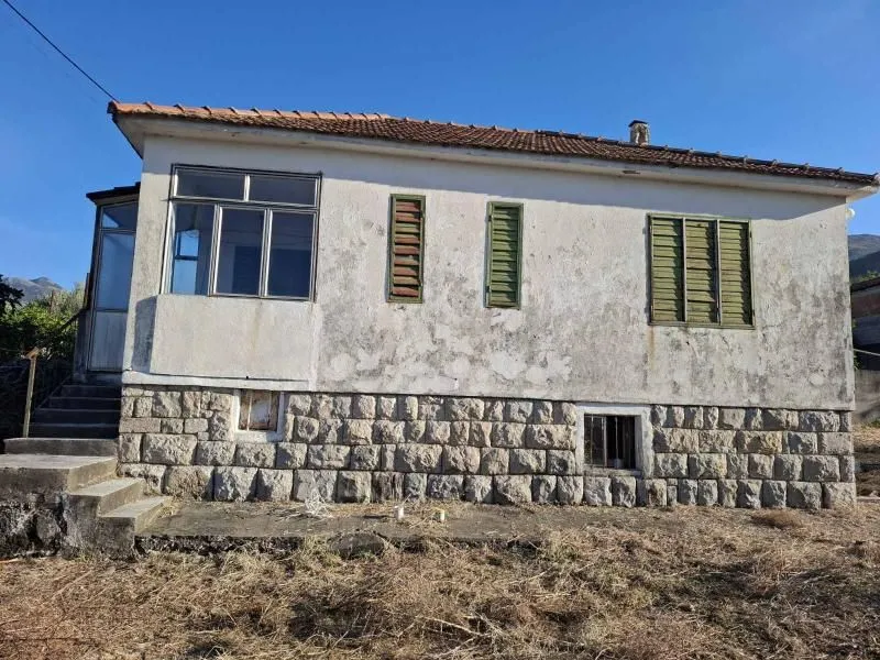 Eksterijer starije prizemne kuće sa kamenim temeljom.