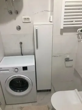 Manje kupatilo sa veš mašinom, WC šoljom i bijelim ormarićem. - image 5