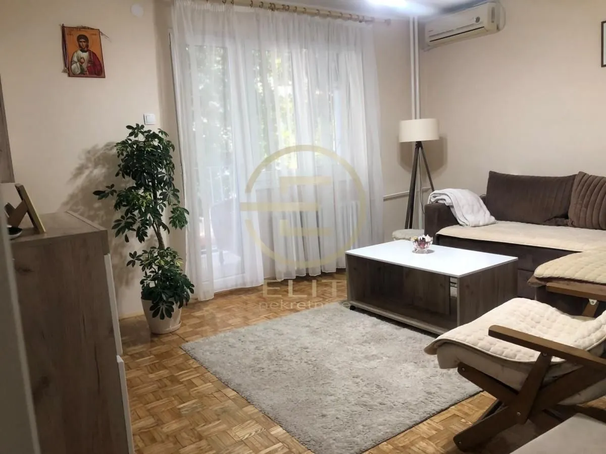 Dnevna soba sa garniturom, stočićem i izlazom na terasu.