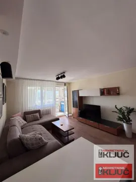 Dnevna soba sa ugaonom garniturom, TV komodom i izlazom na terasu. - image 2