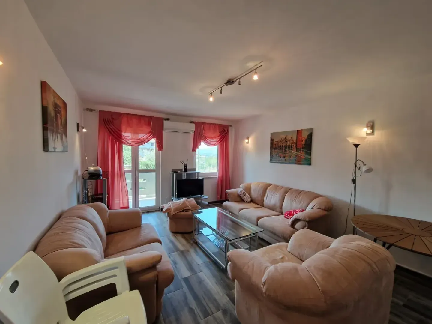 Prostrana dnevna soba sa garniturom za sedenje, stočićem i izlazom na terasu.