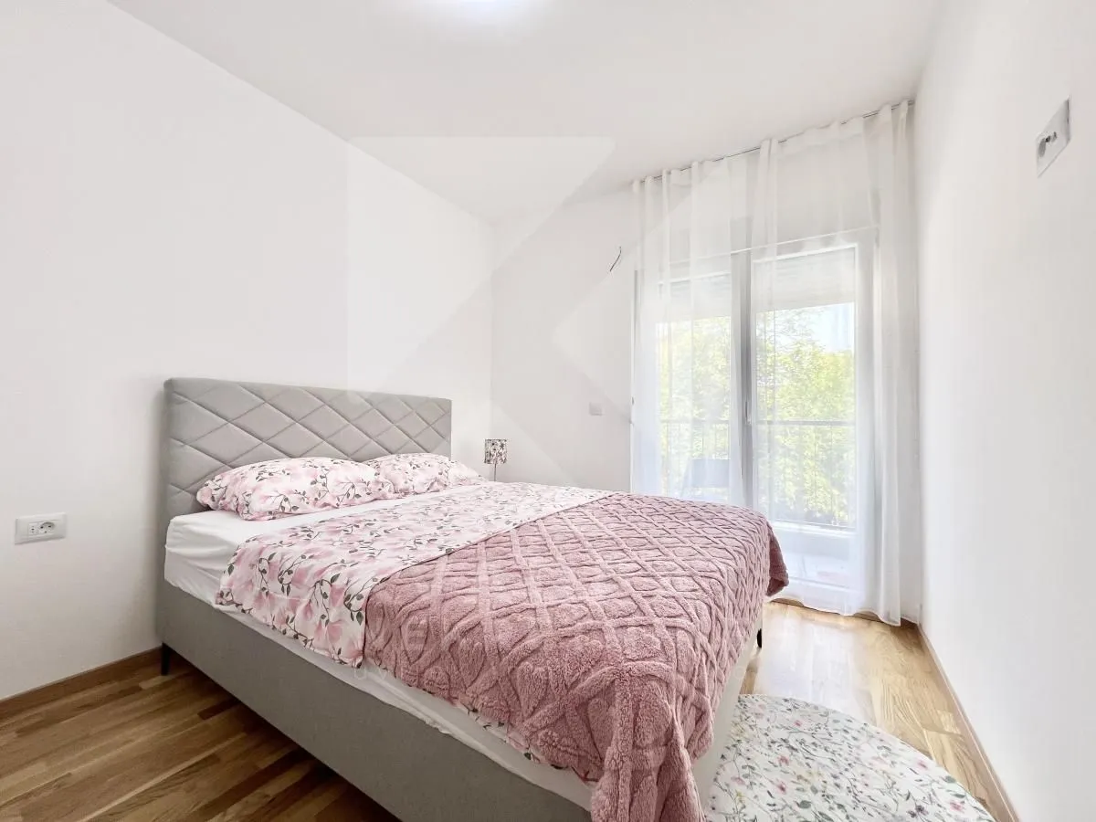 Namještena spavaća soba sa bračnim krevetom i izlazom na balkon.
