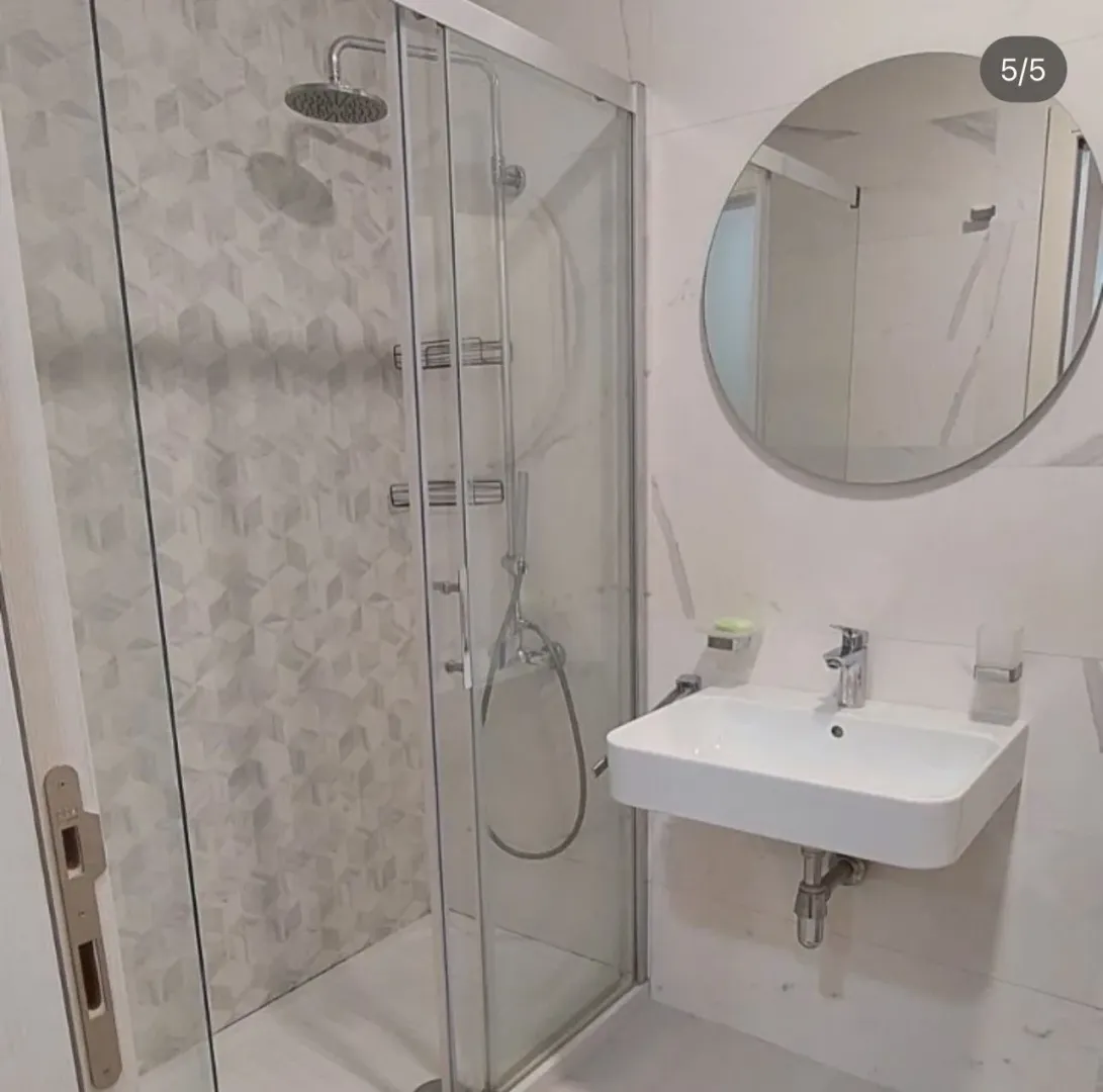 Modernly equipped bathroom with a shower cabin and sink.