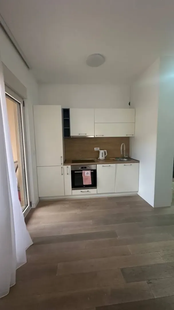 Small modern kitchen with white cabinets and a wooden countertop.