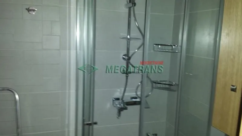 View of the shower cabin in the tiled bathroom.