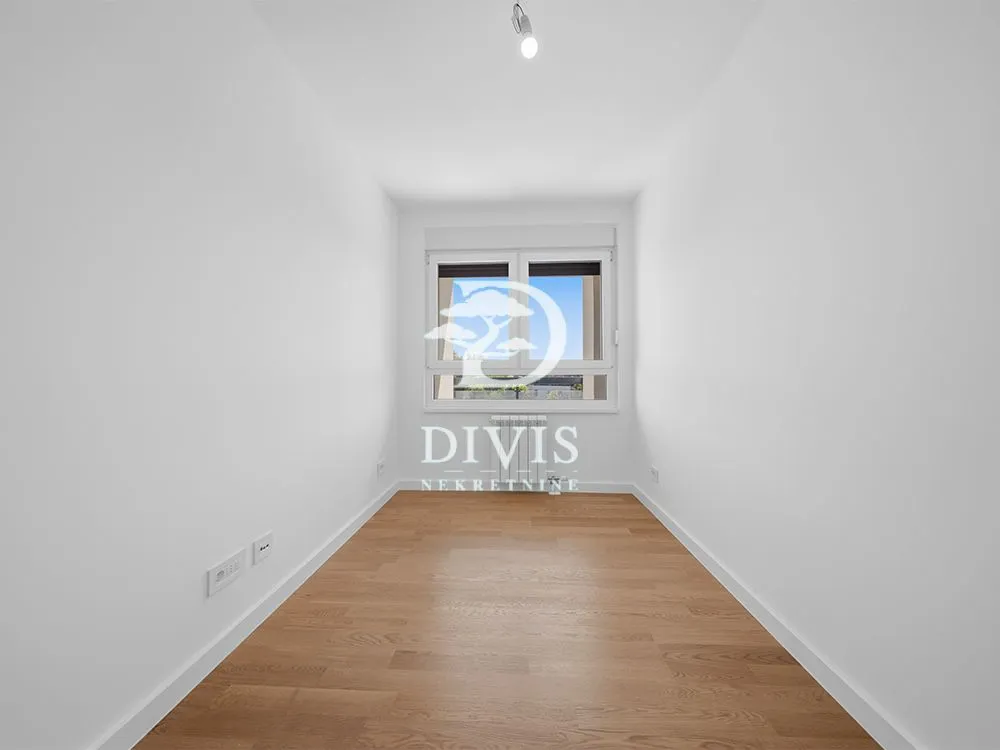 Empty room with white walls, wooden floor, and a window.
