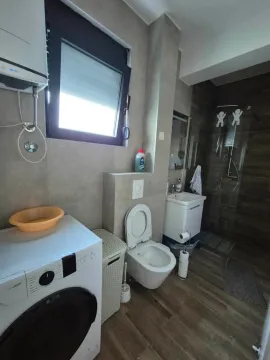 Modern bathroom with a walk-in shower, washbasin, toilet, and washing machine. - image 6
