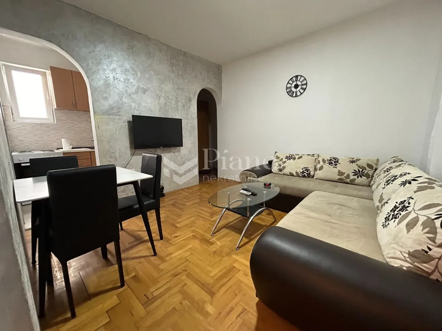 Living room with sofa, dining table, and a view of the kitchen.