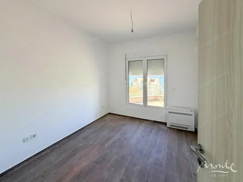 Prazna soba sa drvenim podom, klima uređajem i pogledom kroz prozor. - image 5